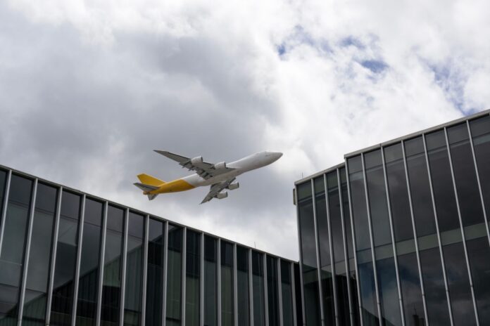 El Dorado ya opera 74 movimientos por hora en una infraestructura pensada para 68, y la Aerocivil suma a Airbus y Avianca para rediseñar el cielo de Bogotá Avión de carga sobrevolando edificios de oficinas en Bogotá