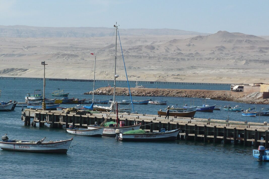 Muelle de pescadores en la bahía de San Juan de Marcona, con el muelle minero y el desierto al fondo