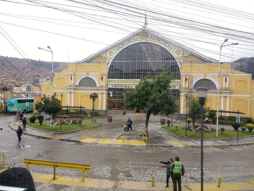 Fachada amarilla de la Terminal de Buses de La Paz, con un bus interdepartamental a la izquierda