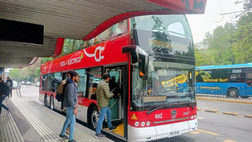 Pasajeros suben por la puerta delantera a un bus eléctrico de dos pisos de Red en la Alameda de Santiago