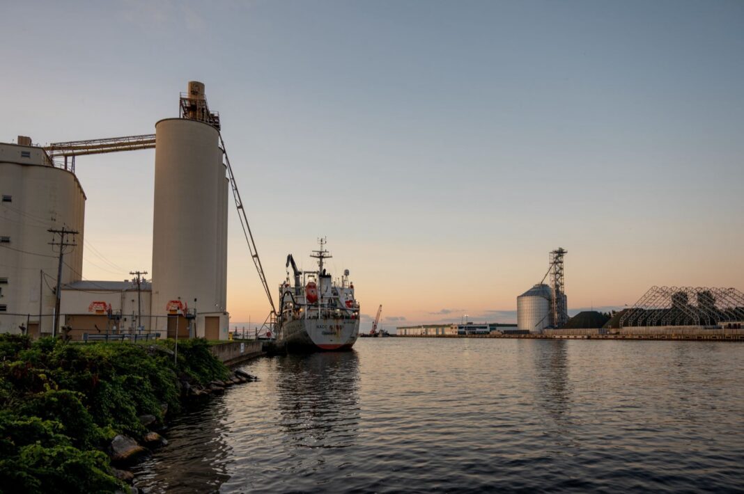 Silos de granos con cinta transportadora junto a un buque atracado en un puerto