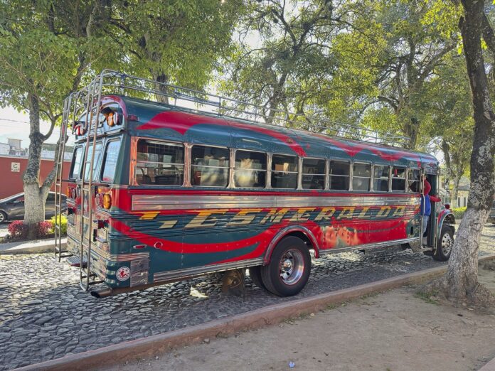 El Congreso de Guatemala rechazó las objeciones al tope de Q39 por galón y Arévalo ya tiene dos decretos de combustibles por firmar Bus extraurbano pintado de rojo y verde estacionado en una calle empedrada de Antigua Guatemala