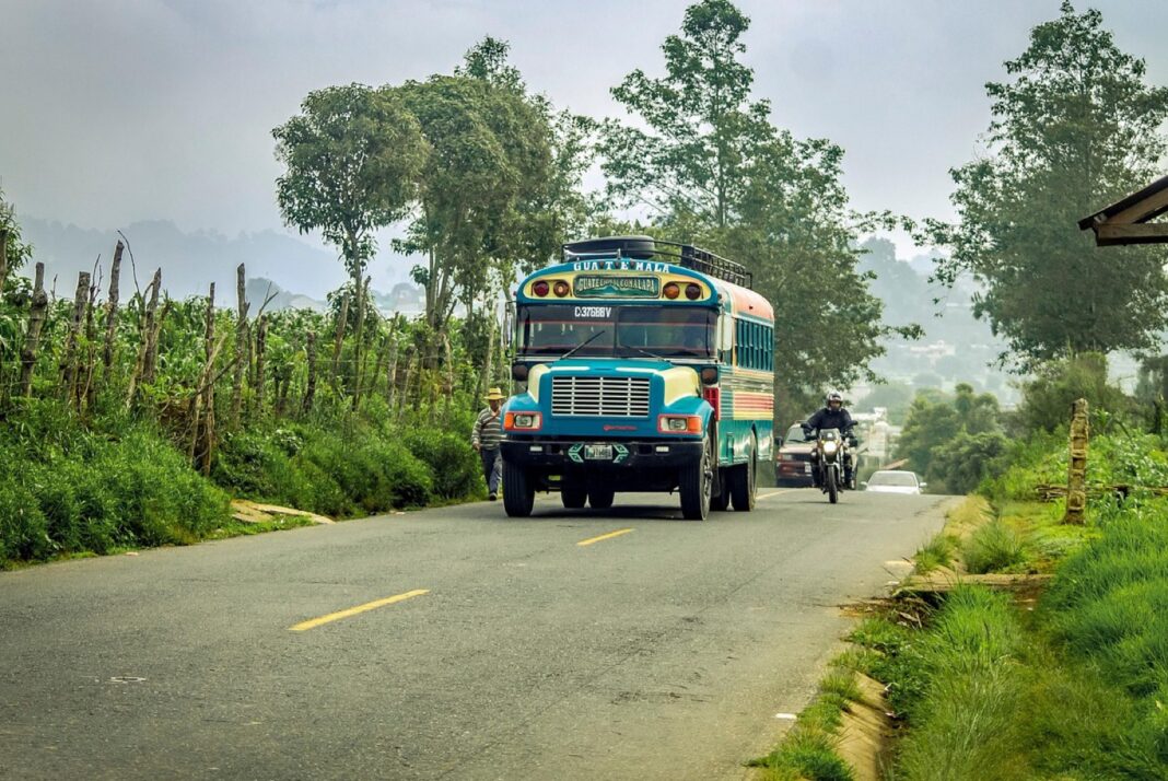 Bus extraurbano pintado de colores en una carretera rural de Guatemala