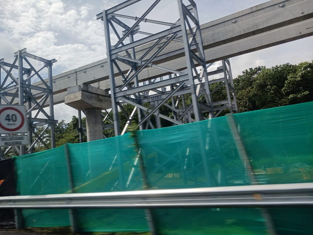 Estructuras metálicas y viga del monorriel de la Línea 3 en construcción junto a una carretera en Panamá Oeste