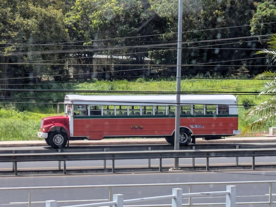 Autobús de pasajeros rojo y blanco circulando por la carretera Panamericana en Panamá