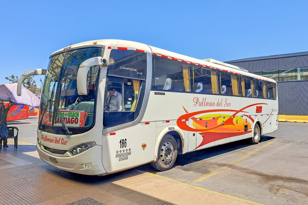 Bus interurbano de Pullman del Sur estacionado en el Terminal Alameda de Santiago, con el conductor en la cabina