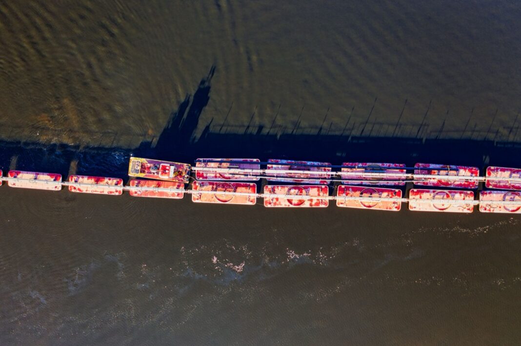 Vista aérea de un convoy de barcazas empujado por un remolcador en un río