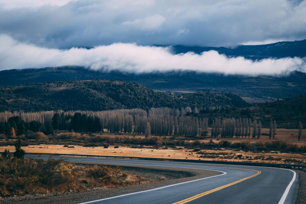 Ruta de montaña en la Patagonia argentina con álamos y nubes bajas