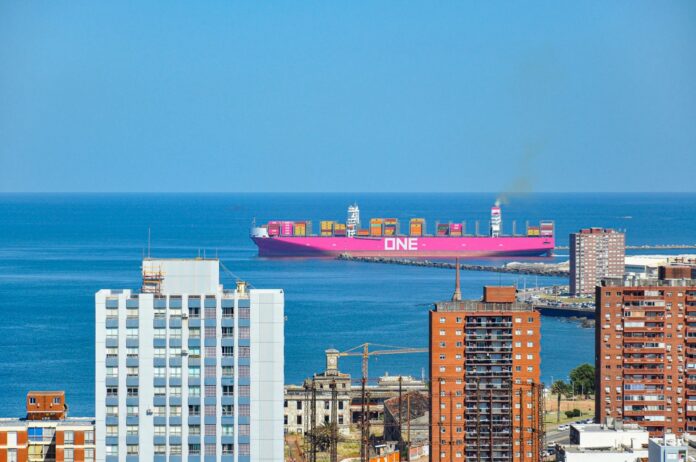Puerto de Montevideo: el Gobierno pone sobre la mesa su propia propuesta y el sindicato vuelve a parar el jueves Buque portacontenedores entrando al puerto de Montevideo, visto entre edificios de la ciudad
