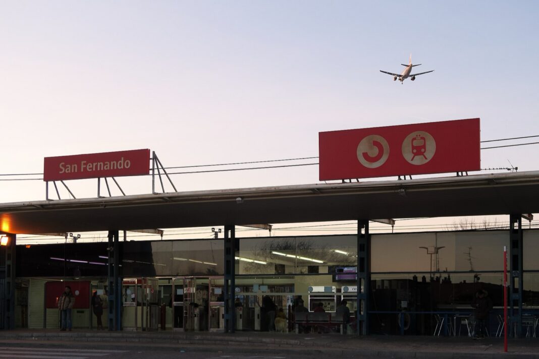 Fachada de la estación de Cercanías de San Fernando, en Coslada, con un avión sobrevolándola