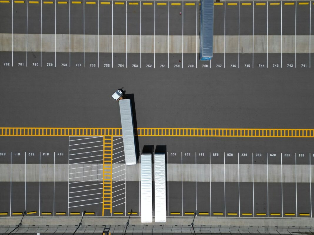Vista aérea de un patio de estacionamiento con cajas de tráiler y un tractocamión maniobrando