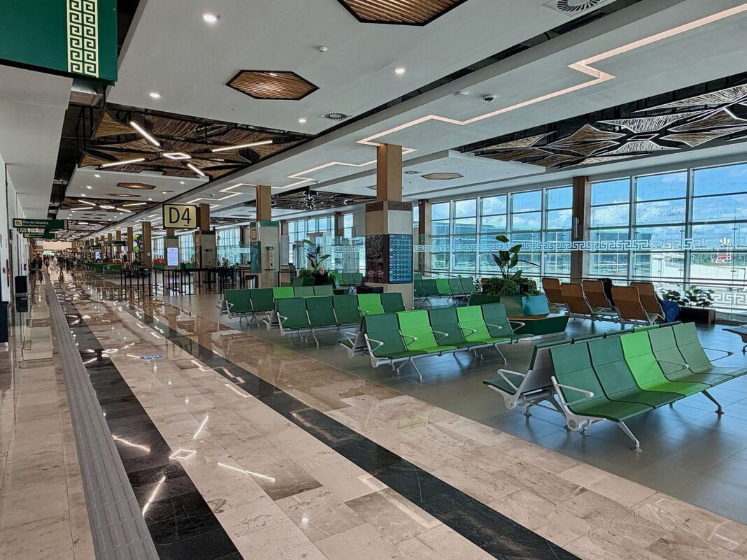 Sala de espera vacía con asientos verdes en el aeropuerto internacional de Tulum
