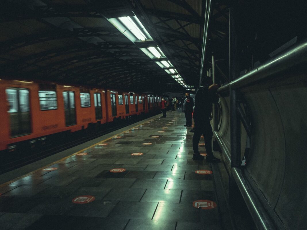 Tren naranja del Metro de la Ciudad de México en un andén con pasajeros esperando