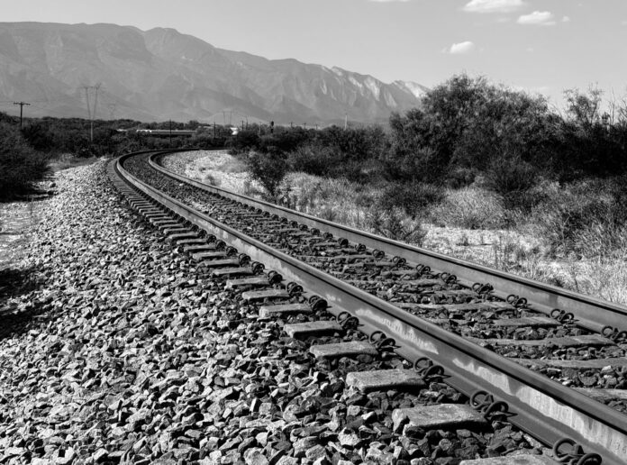 El tren Saltillo-Nuevo Laredo ya liberó sus primeros 15 kilómetros; ahora le toca negociar dentro de la ciudad Vía férrea curva en un paisaje semidesértico con la sierra al fondo, en blanco y negro