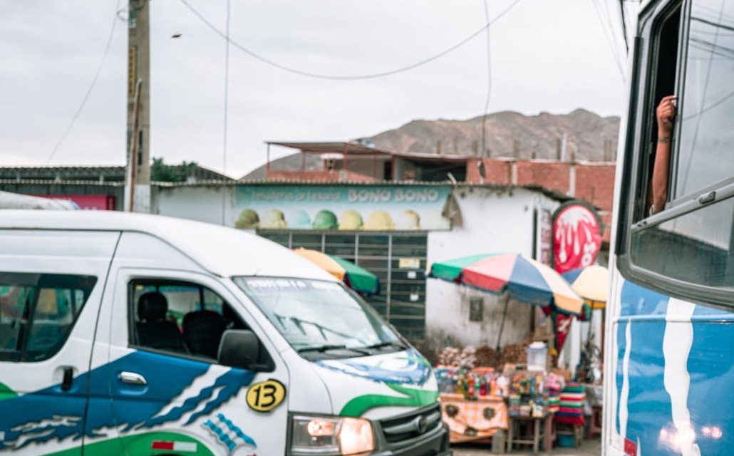 Combi de transporte urbano junto a un bus en una calle de una ciudad del Perú