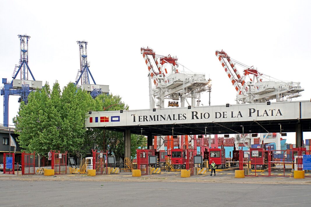 Portones de acceso de camiones a Terminales Río de la Plata, en el puerto de Buenos Aires, con grúas pórtico y contenedores al fondo