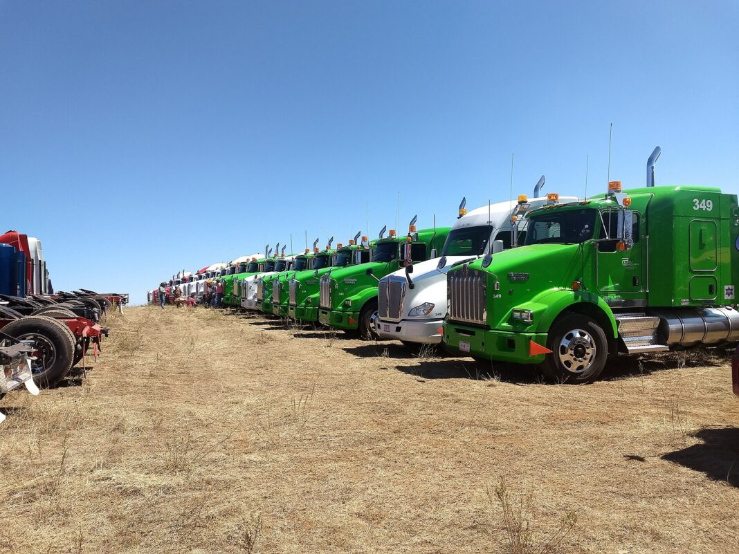 Fila de tractocamiones Kenworth Kenmex estacionados en un llano de Ahuazotepec, Puebla