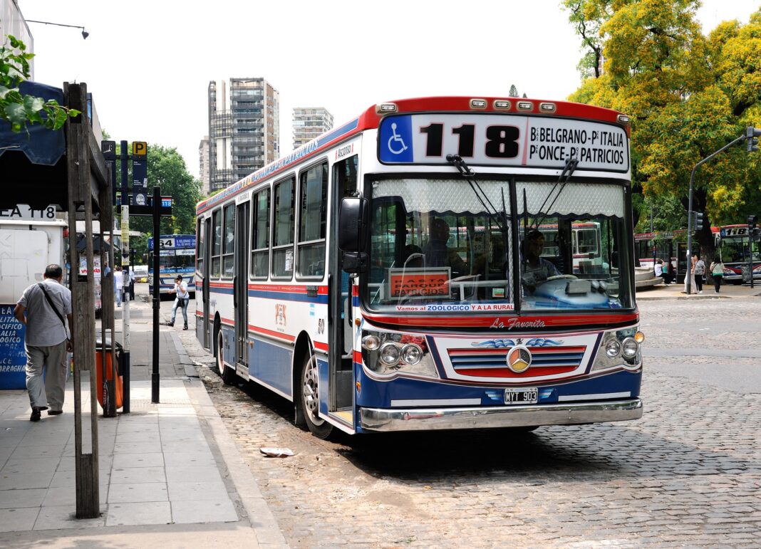 Colectivo de la línea 118 de Buenos Aires, con carrocería roja, blanca y azul, detenido junto a una parada
