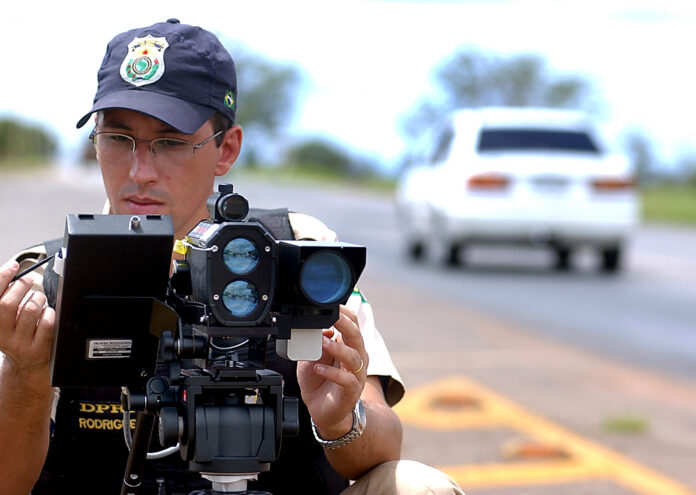 Brasil iba a medir la velocidad promedio entre dos radares y la ANTT lo frenó a Agente de la policía de carreteras de Brasil operando un radar de velocidad sobre un trípode junto a una carretera