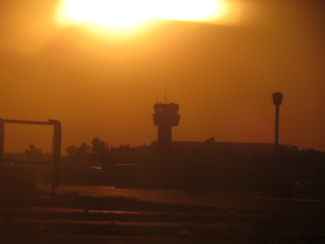 Silueta de la torre de control del Aeropuerto Internacional de la Ciudad de México contra un atardecer anaranjado