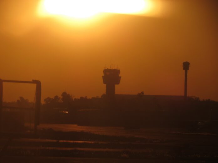Hacienda quiere cobrarles 10% más a las aerolíneas por usar el cielo mexicano, y Silueta de la torre de control del Aeropuerto Internacional de la Ciudad de México contra un atardecer anaranjado