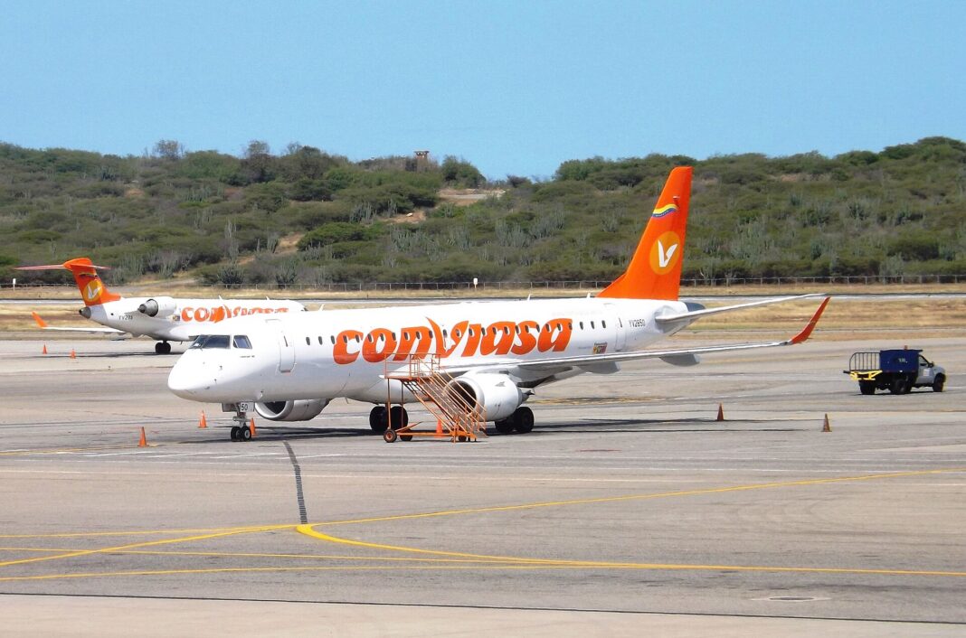 Avión Embraer 190 de Conviasa estacionado en la plataforma del aeropuerto de Maiquetía, con cerros verdes al fondo