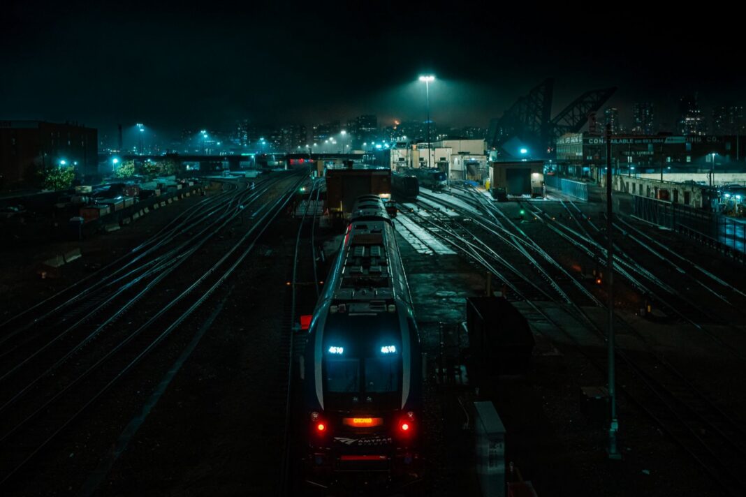 Tren de Amtrak Midwest en un patio ferroviario de Chicago de noche, con el perfil de la ciudad al fondo