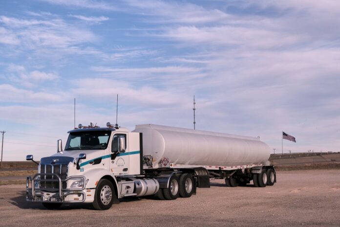 Con el diésel a 6,53 dólares, la Casa Blanca busca alternativas a prohibir las exportaciones y tres estados sacan a la carretera el diésel agrícola Camión cisterna de combustible estacionado en una llanura de Texas con una bandera de Estados Unidos al fondo