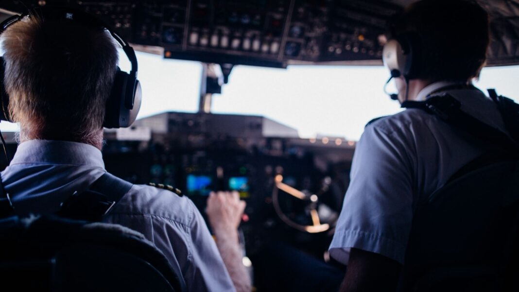 Dos pilotos de espaldas en la cabina de un avión comercial durante el vuelo
