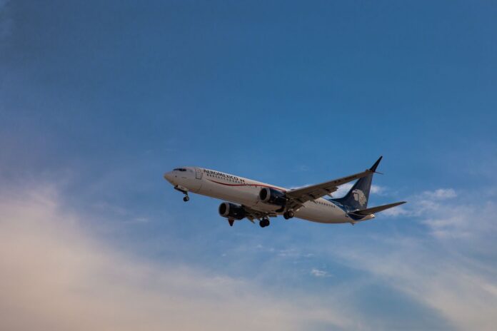 Aeroméxico evalúa rutas a EE.UU.; la carga seguirá en el AIFA Boeing 737 MAX de Aeroméxico en aproximación con el tren de aterrizaje abajo, bajo un cielo azul con nubes altas