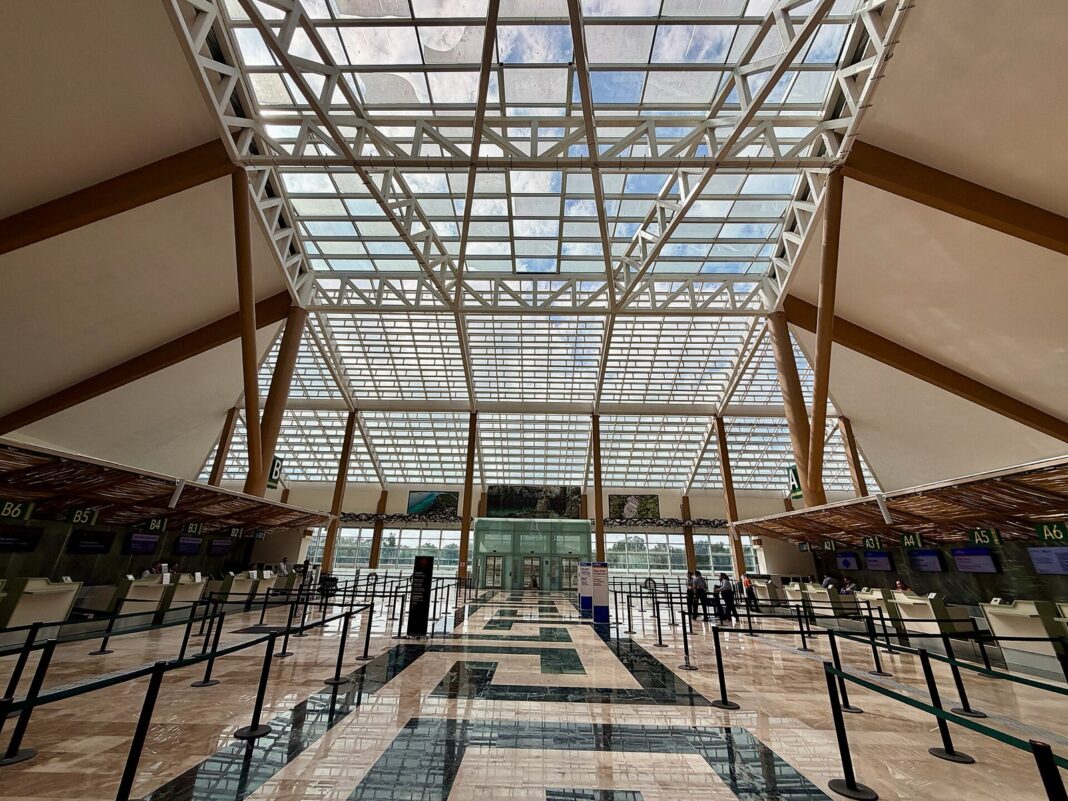 Vestíbulo de documentación del aeropuerto de Tulum casi vacío, con techo de cristal y mostradores