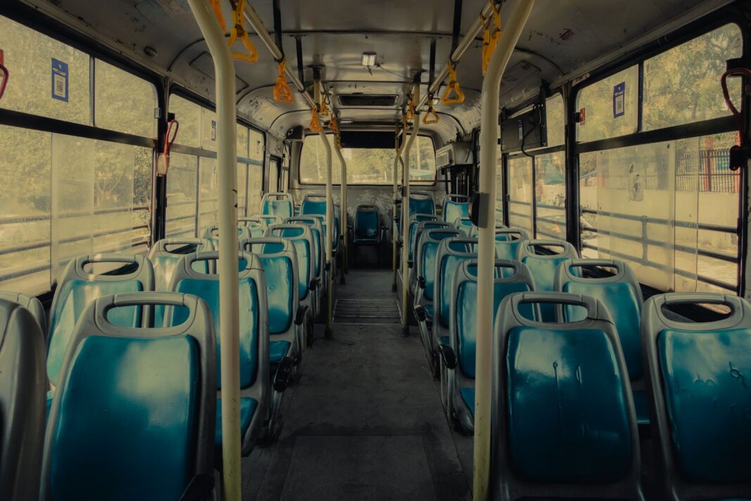 Interior vacío de un autobús urbano con asientos azules y agarraderas amarillas