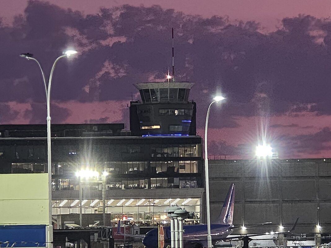 Torre de control del Aeroparque Jorge Newbery al amanecer, con un avión en plataforma