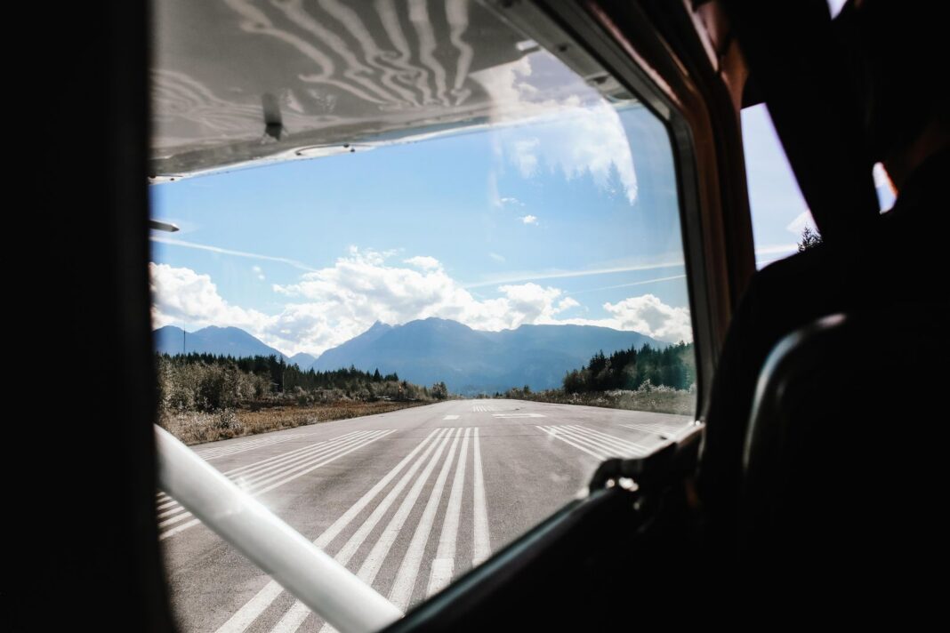 Pista de aterrizaje con montañas y bosque al fondo, vista desde la cabina de una avioneta