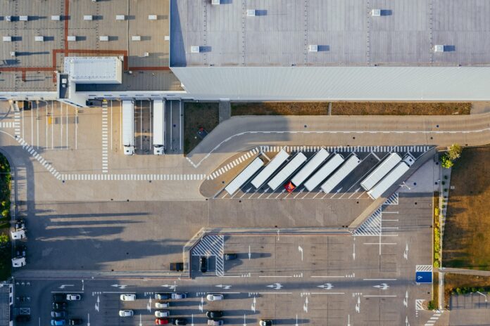 Bancolombia pacta 5 bodegas de la Calle 80 por $500.000 millones Vista aérea de un centro logístico con andenes de carga y tractocamiones estacionados