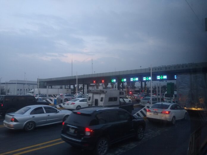 Estímulo por casetas: Diputados fijan el tope en 250 millones Autos y tráileres hacen fila en una plaza de cobro de una autopista en México al atardecer