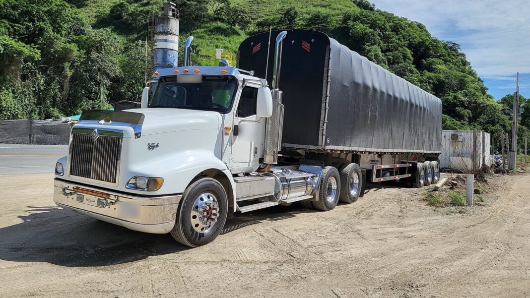 Tractocamión con semirremolque carpado estacionado junto a una carretera en una zona montañosa de Colombia