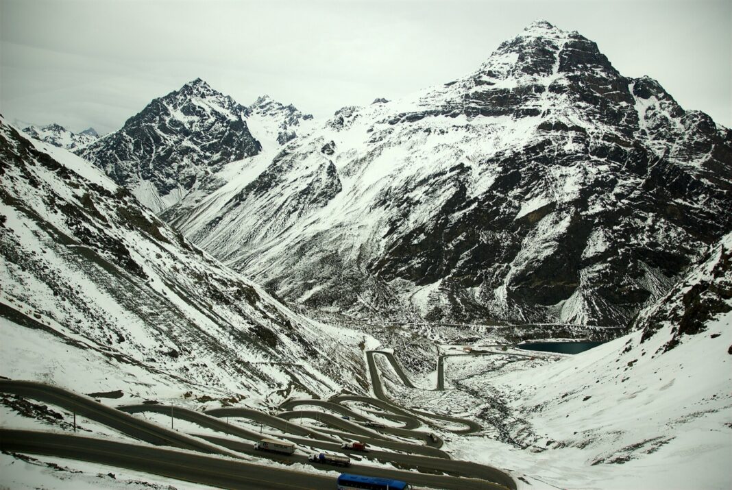 Camiones y un autobús suben las curvas nevadas de Los Caracoles hacia el túnel Cristo Redentor