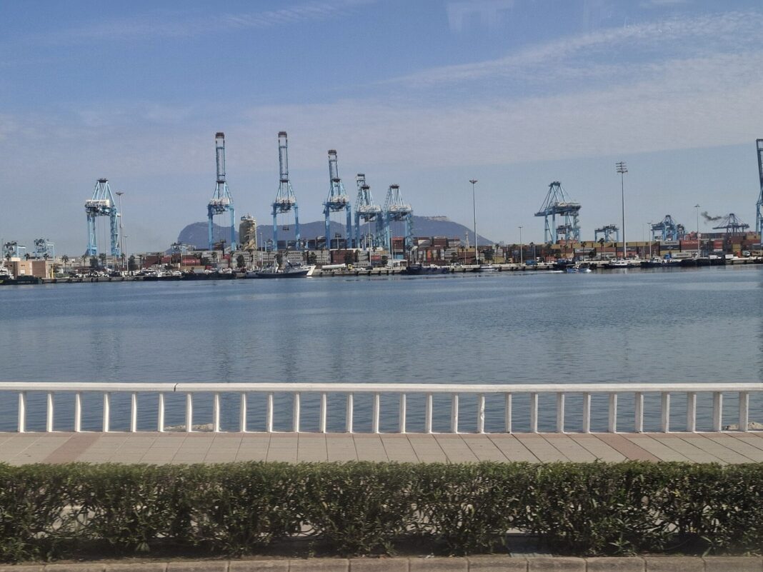 Grúas portacontenedores de la terminal de Algeciras vistas desde el paseo marítimo, con el Peñón de Gibraltar al fondo