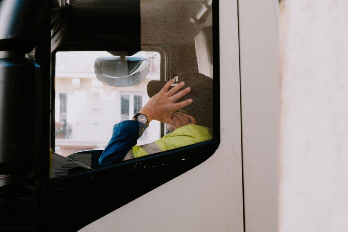 España: el DeCA digital ya es obligatorio y multa hasta 6.000 € Conductor con chaleco reflectante dentro de la cabina de un camión, con documentos en el salpicadero