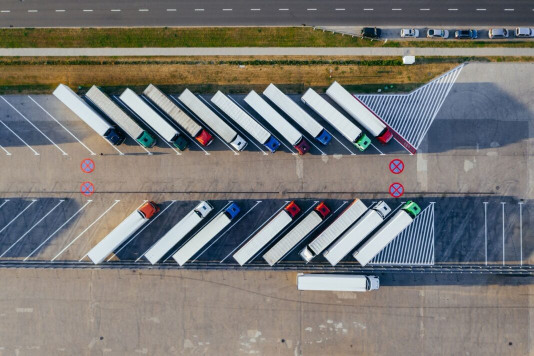 Tractocamiones con semirremolque estacionados en diagonal en un aparcamiento, vistos desde arriba