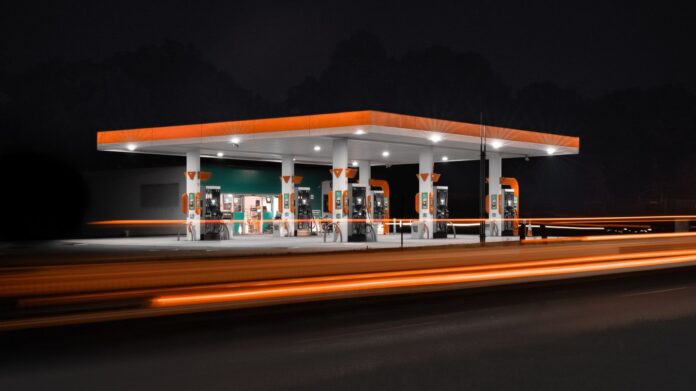 España: el diésel no baja y la gasolina cae hasta 11 céntimos Estación de servicio iluminada de noche junto a una carretera con estelas de luz de vehículos