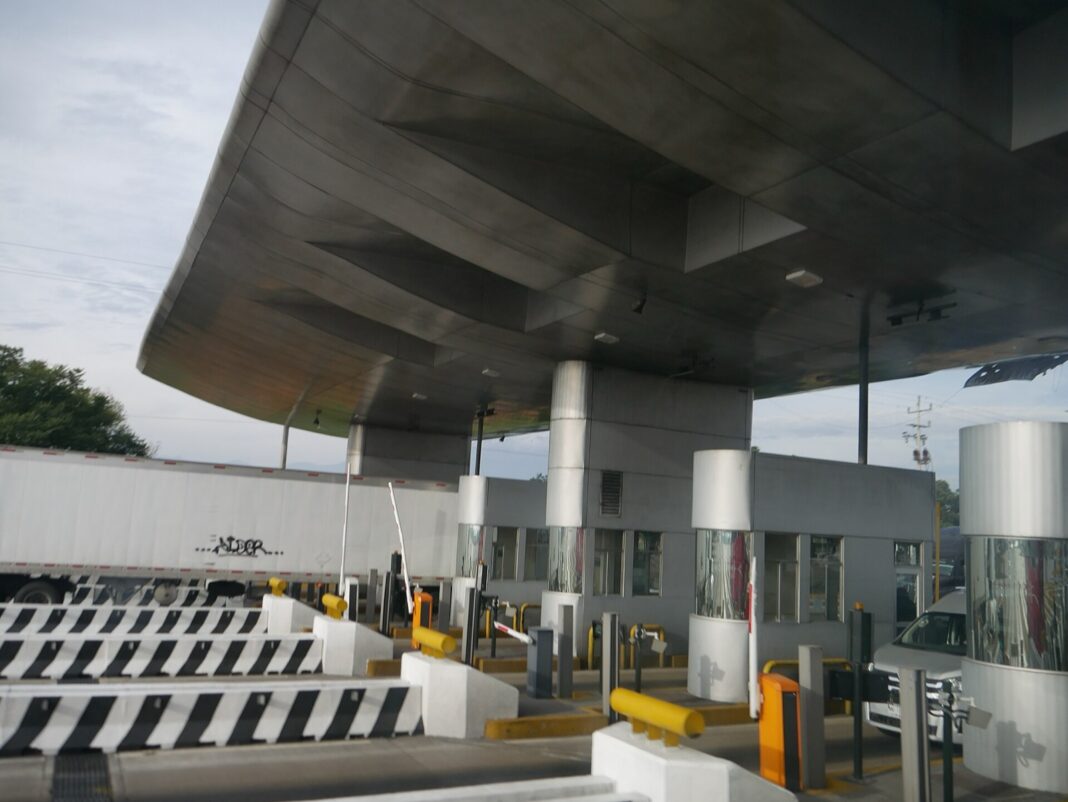 Caseta de cobro de la autopista México-Puebla con un tráiler de caja seca pasando por un carril