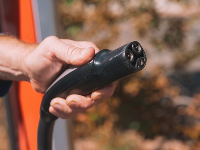 FedEx encarga 2.000 camiones eléctricos a Harbinger por US$300 M Mano sosteniendo el conector de un cargador para vehículos eléctricos
