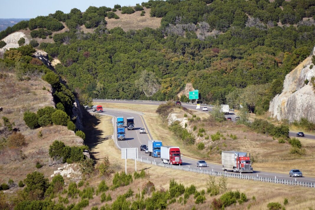 Tractocamiones y autos circulan por la Interestatal 35 entre cerros boscosos de Oklahoma