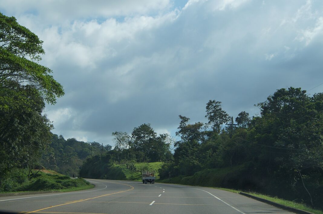 Camión en una curva de la carretera del Norte de Honduras entre colinas con vegetación