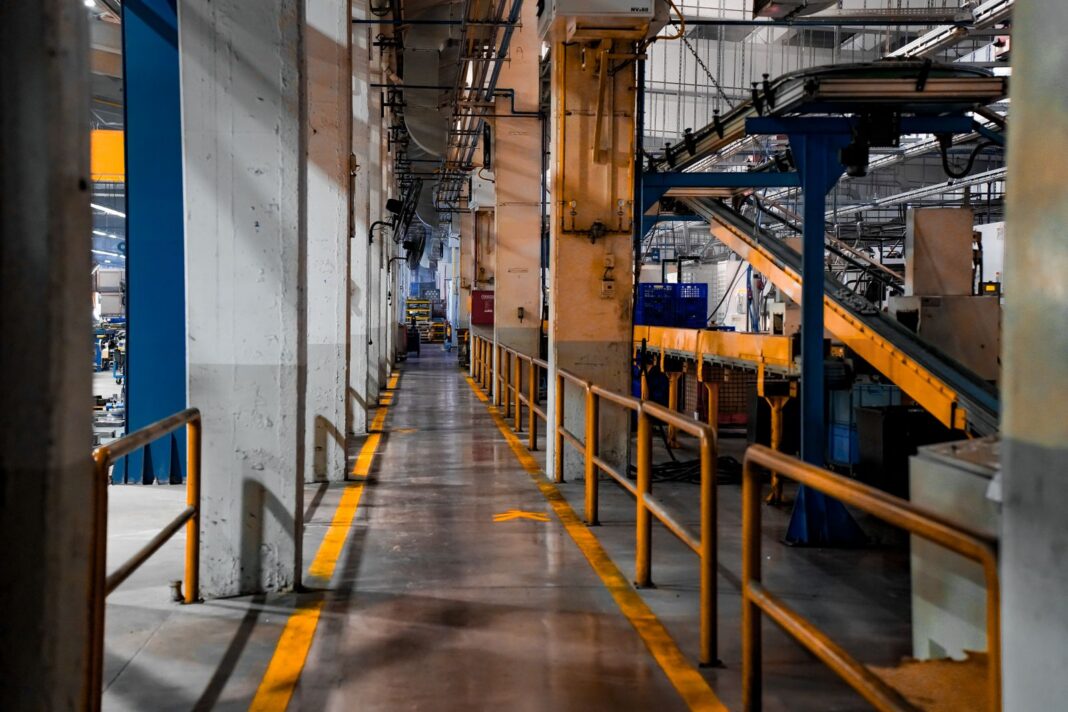 Pasillo vacío dentro de una planta industrial con líneas de producción detenidas