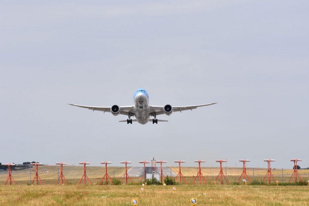 Avión de pasajeros de fuselaje ancho despega sobre las luces de aproximación de una pista