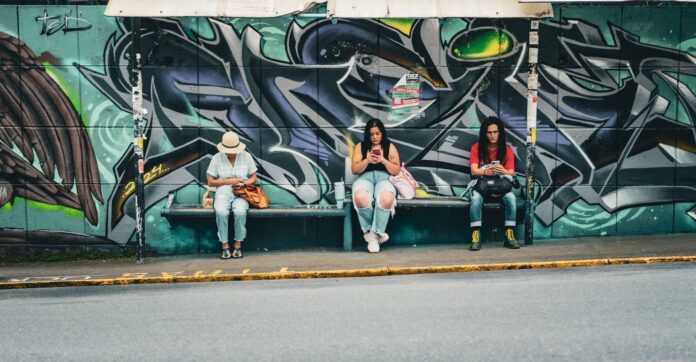 San José: Lared deja la ruta 16 y cinco barrios quedan sin bus Tres personas esperan el bus en una parada con grafitis en San José, Costa Rica