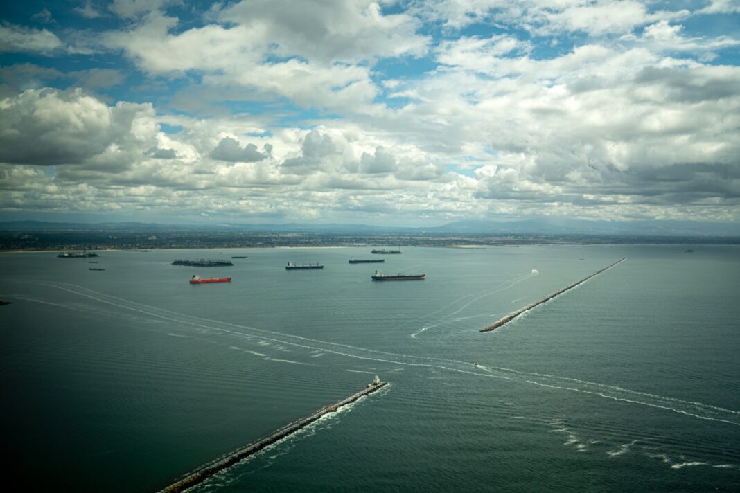 Buques fondeados frente a la escollera de la bahía de San Pedro, vistos desde el aire bajo un cielo con nubes